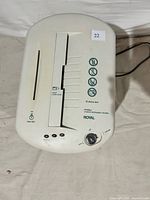 Top view of a white Royal paper shredder showing feed slot, rotary dial, buttons, and safety instructions.