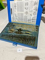 Open view of the Mastercraft tap and die set showing various taps, dies, and handles arranged inside the blue case with instruction sheet under the lid.