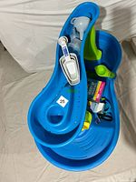 Water play table seen from top with several toys and scoops placed inside. Bright blue and green plastic construction with scooping tools and buckets.