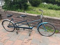 Full side view of tandem bicycle showing frame, seats, handlebars and drivetrain