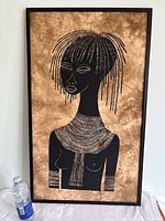 Full view of the framed African batik print artwork with water bottle for size reference.