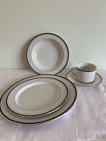 Photo showing a selection of plates, cups, and saucers arranged to display the design and rim detail.