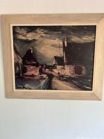 Full view of the framed art print depicting a Normandy village with houses and a cloudy sky in muted dark tones.