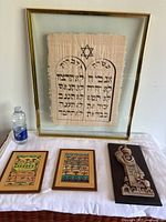 Framed papyrus print of the 10 Commandments and three wall hangings including two reproductions and a carved plaque.