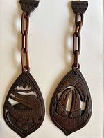 Front view of two wooden carved wall hangings with chain links, depicting an alligator and a bird feeding its young