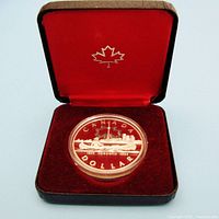 Silver dollar coin commemorating Toronto's 150th anniversary, displayed in opened presentation case with red velvet interior and maple leaf symbol.