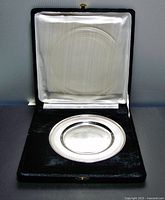 Plate sitting in fitted black velvet hinged box with white satin lid interior