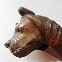 Side close-up of the carved wooden bear nutcracker's face showing detailed carving and glass eye