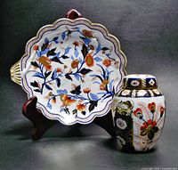 Shell-handled dish and potpourri vase shown together against dark background on stands.