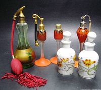 Full lot showing six perfume bottles including porcelain, glass orange, green glass atomizer with red bulb and hose.