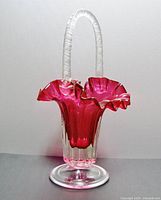 Front view of cranberry cased art glass basket showing ruffled top and decorative handle.