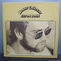 Front of the vinyl album showing the beige cover with a black and white close-up photo of Elton John wearing sunglasses, titled 'Honky Chateau Elton John'.