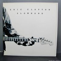 Front cover of Eric Clapton Slowhand 1977 vinyl showing black and white image of Clapton playing guitar and album title.