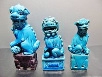 Front view of three ceramic Chinese Foo Dogs in different blue glazes and sizes