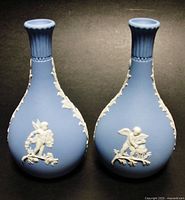 Front view of the pair of blue Wedgwood jasperware bud vases showing the cherub putti reliefs on each.
