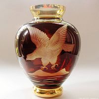 Front view showing the engraved eagle in flight on the red cut to clear glass vase with gold accents on rim and base.