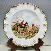 Full view of the Royal Crown Derby cabinet plate on a wooden stand, showcasing the hunting scene and decorative border.