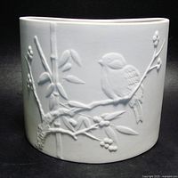 Front view showing bird on branch high relief design and curved form of white bisque vase.