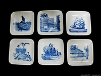 Six square blue and white ceramic plates showing different Danish scenes arranged in two rows, all with smooth rounded corners and wall mounting holes.