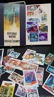 Photo showing space-themed postage stamps displayed on a white backing inside a blue folder with Russian text and rocket illustration on the cover.