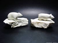 Two white marble polar bear sculptures on rough stone bases viewed from left front angle