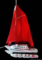 Front view of the vintage chrome sailboat lamp showing red aluminum sails and wave-textured base.