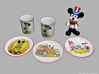 Full view of all items in lot: 1 ceramic Mickey Mouse Uncle Sam figurine, 2 Mickey Mouse tumblers, and 3 Disney character plates.