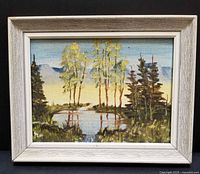 Front view of the vintage miniature oil painting on board showing trees, pond, mountains and sky in a whitewashed wood frame.