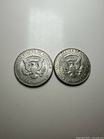Obverse and reverse of two 1964 Kennedy half-dollar coins showing presidential profile and the seal.