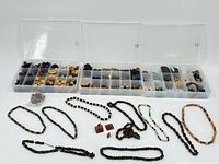Photo of three open clear plastic bead organizer boxes with multiple small compartments containing assorted beads and findings. Several bead necklaces and bracelets are laid out in front of the boxes.