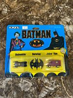 Photo of three Batman and Joker toy cars in sealed original packaging showing front view.