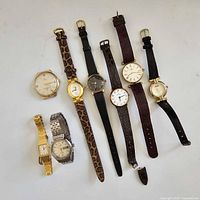 Eight vintage ladies wristwatches of various styles, leaning downwards on a white background.
