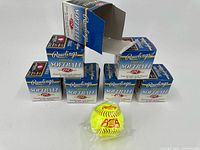 Seven unopened Rawlings Official Softball boxes displayed with one ball unboxed, showing yellow softball with red stitching and ASA logo.