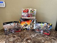 Four Disney Infinity toys arranged on countertop showing two Star Wars 3.0 Edition packs, Pixar Cars set, and Buzz Lightyear figure in packaging.