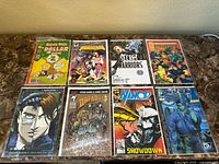 Group view of all 8 miscellaneous comic books laid out on table, showing varied titles and colorful covers
