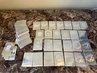 Group of multiple rectangular holographic baseball stickers laid out on a table, showing various MLB team logos and designs in holographic silver finish.