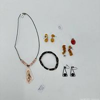 Overview of the entire group showing the necklace, bracelet, red stone pendant, and three pairs of earrings arranged on a white surface.
