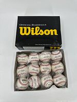 Box containing one dozen Wilson baseballs, showing yellow Wilson logo and text on black box.