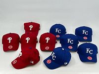 Photo showing all 10 baseball caps arranged with 5 Phillies red hats and 5 Royals blue hats.