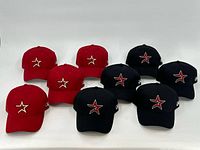Set of nine baseball caps in red and black with Houston Astros logo on front, arranged for photo.