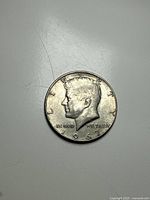 Obverse side of the 1967 Kennedy half dollar coin showing JFK's left profile and date.