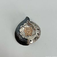 Front view of sterling silver and 18k gold pendant showing traditional Peruvian emblem and hammered texture.