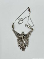 Front view of vintage sterling silver fairy pendant on chain with mother of pearl and garnet beads.