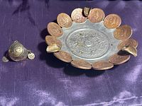 Photo showing both the ashtray and the brass ring on a purple fabric background.