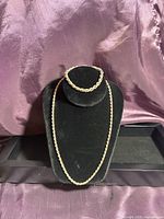 Front view of sterling silver rope chain necklace and matching bracelet on black velvet display against a satin background.