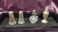 Full set of four salt and pepper shakers: Two silver, one clear crystal with silver top and handle, one ornate silver shaker