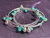 Six bracelets on a dark purple fabric background showing turquoise and sterling silver beads arranged in a stack.