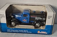 Front and side view of the boxed die-cast 1937 Chevrolet Tanker Bank model with Amoco branding in blue and black, showing Limited Edition 1993 label.