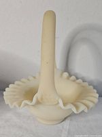Front angled view of custard glass basket showing ruffled edges and handle.