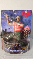 Front view of G.I. Joe U.S. Air Force Crew Chief action figure in sealed packaging showing figure kneeling with rifle.